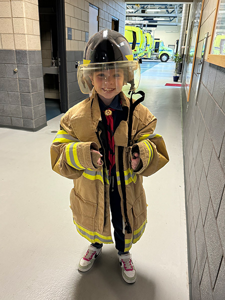 Scout trying on fire fighter equipment at a fire station