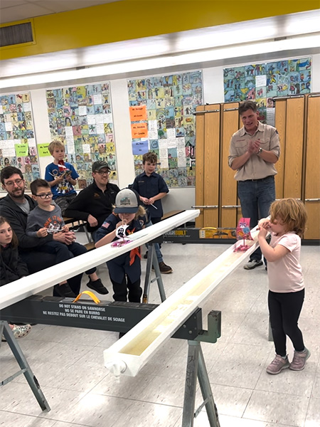 Scouts blowing their regatta boats down a rain gutter